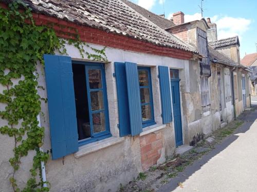 una casa vieja con persianas azules en una calle en petite maison de village, en Ygrande