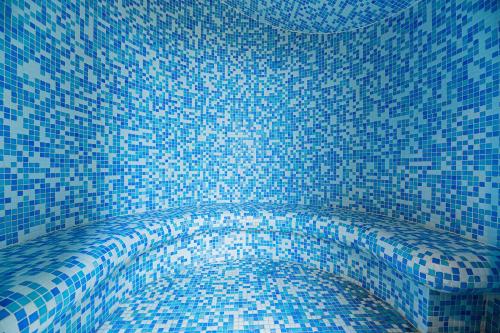 a bathroom with a blue tiled floor with a shower at Hotel Amalia in Smokovce