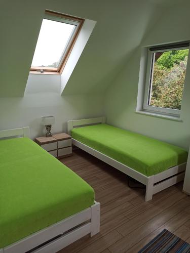 a bedroom with two green beds and two windows at Bałtyckie domki Kopalino in Kopalino