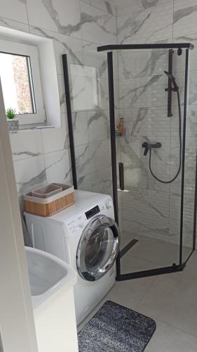 a washing machine in a bathroom with a shower at Bałtyckie domki Kopalino in Kopalino