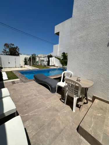 a patio with a table and chairs next to a pool at Coquette villa avec piscine in Tunis