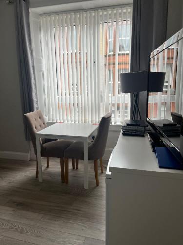 een tafel en stoelen in een kamer met een raam bij Largs Apartment, Spacious & Modern 1 Bed near beach & shops in Largs