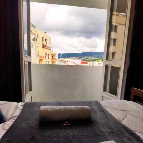 a bed with a towel on it in front of a window at Liberdade Home Royal direito in Braga