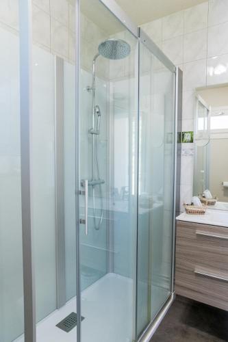 une douche en verre dans une salle de bain avec un lavabo dans l'établissement le Relais des Tuileries, à Séreilhac