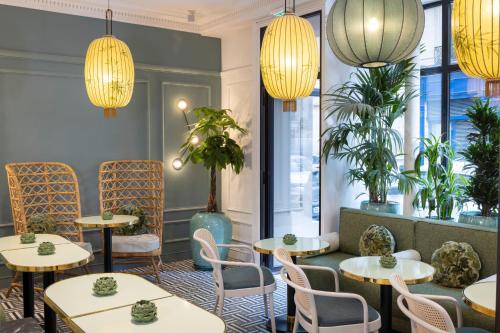 パリにあるHôtel Le Lavoisier & Spaのテーブルと椅子とシャンデリアのあるレストラン