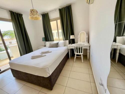 a bedroom with a bed and a table with a chair at Eliza Suite at Pernera Beach in Protaras
