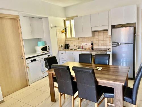 a kitchen with a wooden table and black chairs at Eliza Suite at Pernera Beach in Protaras