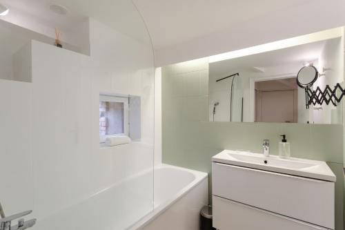une salle de bain blanche avec un lavabo et une baignoire dans l'établissement Appartement la vie en rose - Centre historique, à Rennes