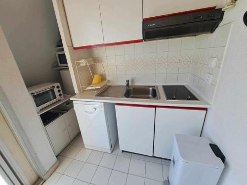 une petite cuisine avec un évier et un micro-ondes dans l'établissement Appartement 1 chambre et mezzanine, 4-6 couchages, parking privé - FR-1-326-505, à Marseillan
