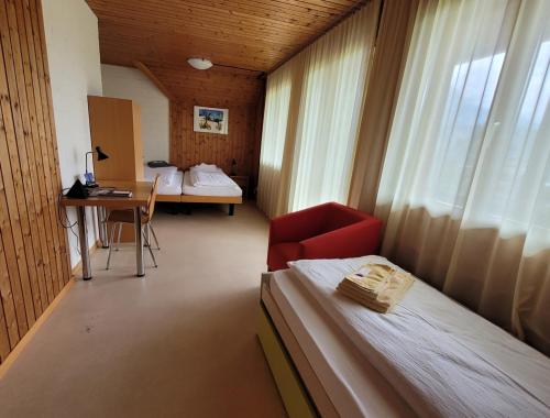 Habitación con 2 camas, escritorio y ventana. en B&B Hotel Mattli Übernachtung Frühstück, en Morschach