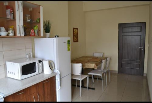 ウクフにあるArkadia Noclegiのキッチン(白い冷蔵庫、テーブル、椅子付)