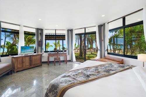 ein Schlafzimmer mit einem Bett, einem Schreibtisch und Fenstern in der Unterkunft Anahata Resort in Lipa Noi