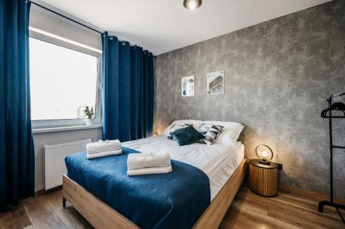 1 dormitorio con cama con sábanas azules y ventana en Apartamenty Krakowska 24 z ogródkiem, en Ostrów Wielkopolski