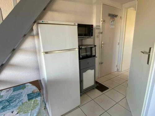 une petite cuisine avec un réfrigérateur et un micro-ondes dans l'établissement Appartement climatisé pour 6 avec piscine, terrasse et parking près de la plage - FR-1-326-793, à Marseillan