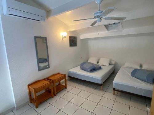 une chambre avec deux lits et un ventilateur de plafond dans l'établissement Appartement climatisé pour 6 avec piscine, terrasse et parking près de la plage - FR-1-326-793, à Marseillan