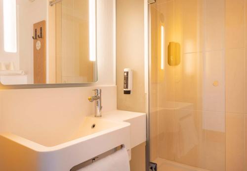 La salle de bains blanche est pourvue d'un lavabo et d'une douche. dans l'établissement B&B HOTEL Martigues Port-de-Bouc, à Port-de-Bouc