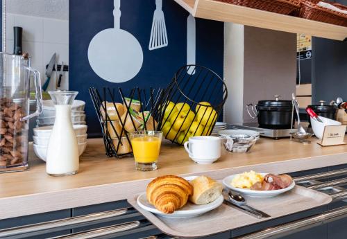 a kitchen counter with a breakfast of croissants and orange juice at B&B HOTEL Grenoble Centre Verlaine in Grenoble