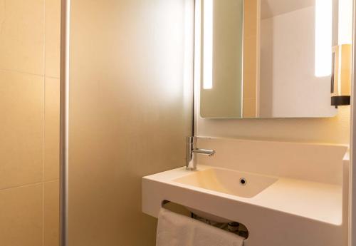 La salle de bains blanche est pourvue d'un lavabo et d'un miroir. dans l'établissement B&B HOTEL Aix-en-Provence Le Tholonet, à Aix-en-Provence
