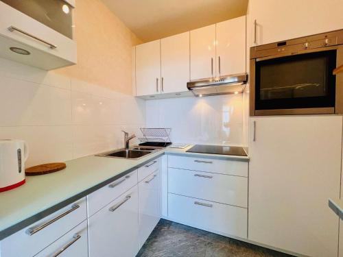 une cuisine avec des armoires blanches, un évier et un micro-ondes dans l'établissement Quiberon - Studio 38m² avec Balcon face mer et Parking - FR-1-478-294, à Quiberon