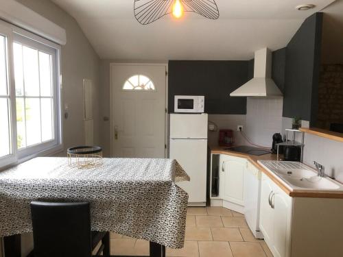 uma cozinha com uma mesa e um frigorífico branco em Domaine de la RIMBERTIÈRE em Thuré