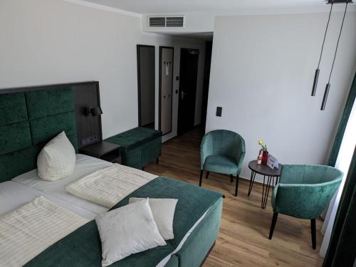 a bedroom with a bed and two chairs and a table at Seehotel Ecktannen in Waren