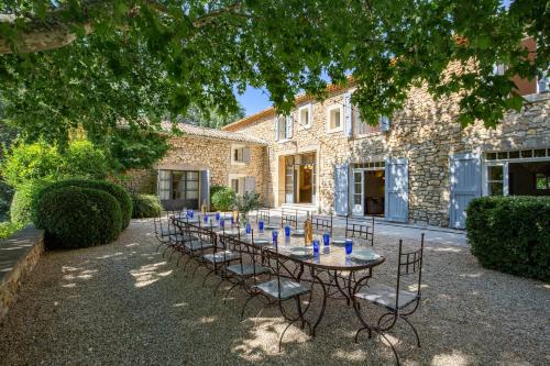 une grande table avec des chaises devant un bâtiment dans l'établissement La Grande Verrière - MH, à Goult