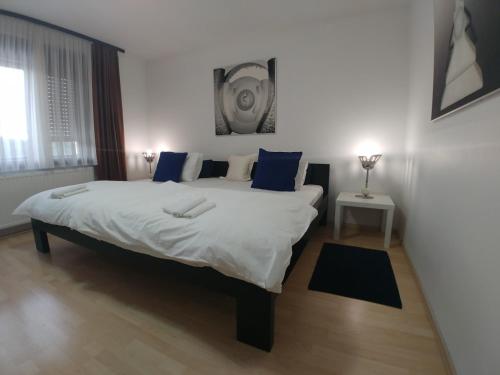 a bedroom with a large white bed with blue pillows at Apartman Arena in Štrigova