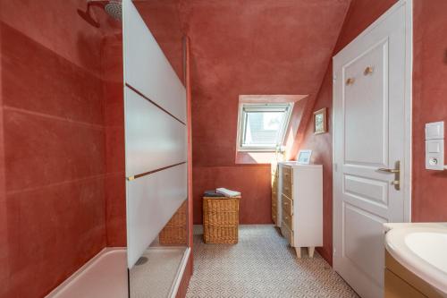La salle de bains est pourvue de murs rouges, d'un lavabo et d'une porte blanche. dans l'établissement Studio 2 ATELIER VINCI, à Amboise