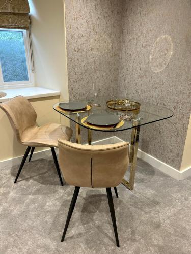 a dining room with a glass table and two chairs at Oasis Boutique New Luxury Apartment , 5 Minutes To Lake Windermere in Bowness-on-Windermere
