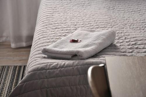 a white bed with a towel on top of it at Q Apart Meta -1, 2 lub 3-pokojowe, klimatyzowane apartamenty przy Manufakturze z garażem lub parkingiem Gratis, FV in Łódź
