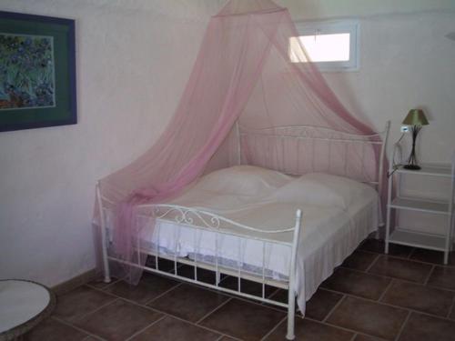 un petit lit avec un baldaquin rose dans une chambre dans l'établissement Romantische Bauernhofvilla inmitten der Weinberge, à Salles-d'Aude