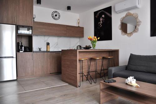 a living room with a couch and a kitchen at Q Apart Meta -1, 2 lub 3-pokojowe, klimatyzowane apartamenty przy Manufakturze z garażem lub parkingiem Gratis, FV in Łódź