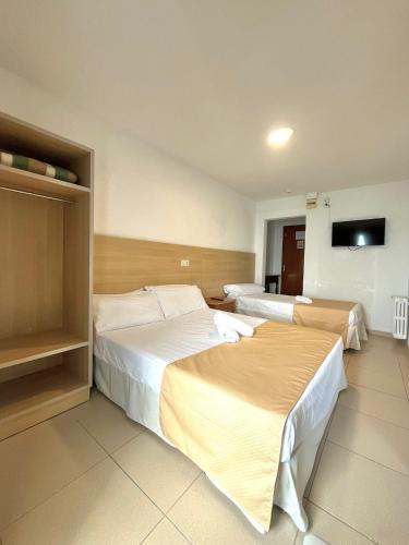 um quarto de hotel com duas camas e uma televisão de ecrã plano em Hostal Mozaik Playa em Lloret de Mar