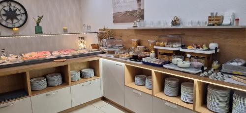 a buffet line with plates and food on display at Hotel Am Deich in Norddeich