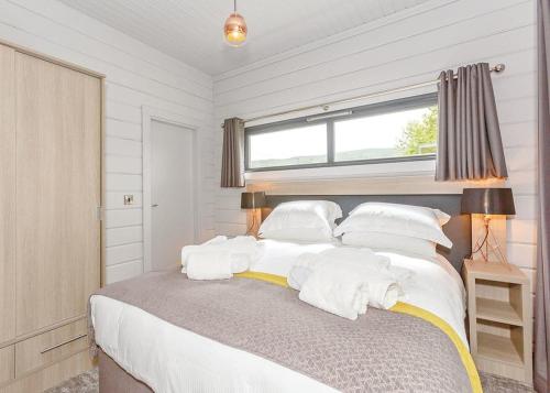 a bedroom with a bed with white pillows and a window at Aysgarth Lodges in Aysgarth