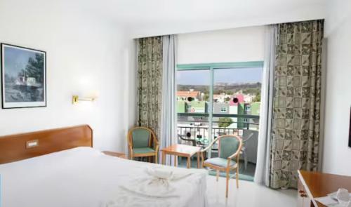 1 dormitorio con cama y vistas a un balcón en Antigoni Hotel, en Protaras