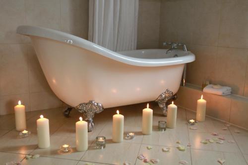 a bathroom with a tub and candles on the floor at Aherlow House Hotel & Lodges in Aherlow