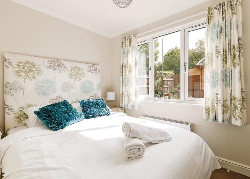 - une chambre dotée d'un lit blanc avec des oreillers bleus et d'une fenêtre dans l'établissement Bucklegrove Holiday Park, à Rodney Stoke