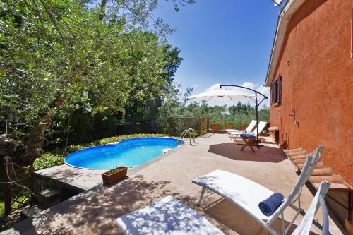 a swimming pool in a yard with chairs and an umbrella at Casale Pontarello - Happy Rentals in Vetralla