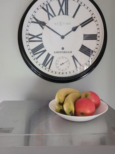 a clock and a bowl of fruit on a table at Kirkstyle Hideaway in Arbroath