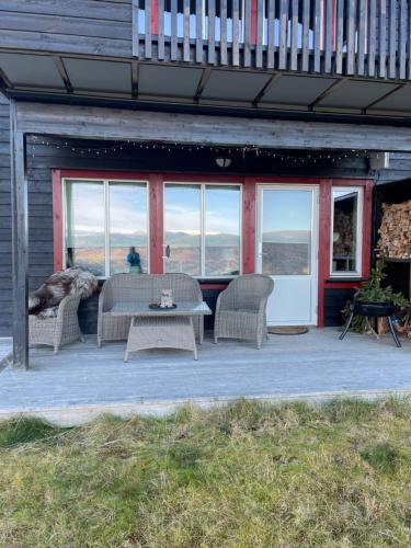 eine Terrasse mit einem Tisch, Stühlen und einem Hund in der Unterkunft Voss Resort Bavallstunet in Skulestadmo