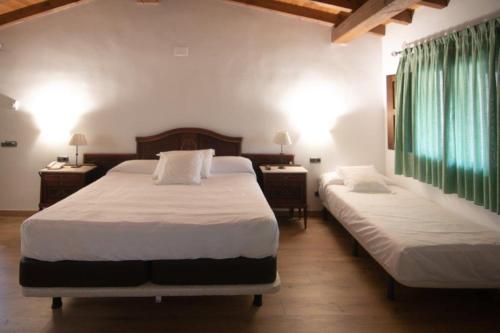 a bedroom with two beds and two tables with lamps at Hospedium Hotel Rural Abadía de Yuste in Cuacos de Yuste