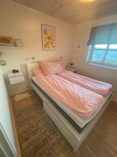 a bedroom with a bed with pink sheets and a window at Voss Resort self-service apartments in Skulestadmo