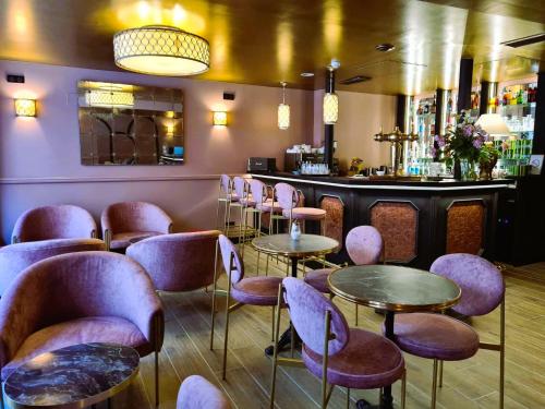 - un bar avec des tables et des chaises pourpres dans une pièce dans l'établissement Logis Hôtel Le Boudoir, à Belvès