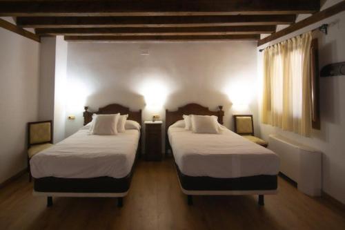two beds in a hotel room with two beds sidx sidx sidx at Hospedium Hotel Rural Abadía de Yuste in Cuacos de Yuste