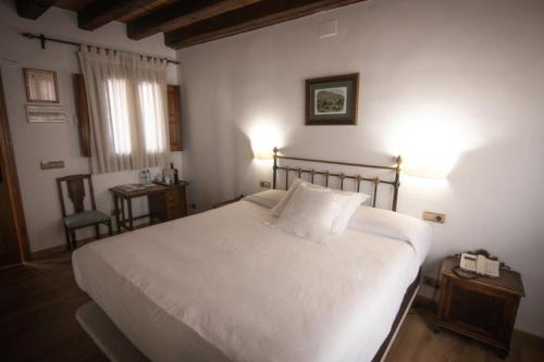 a bedroom with a large white bed and a table at Hospedium Hotel Rural Abadía de Yuste in Cuacos de Yuste