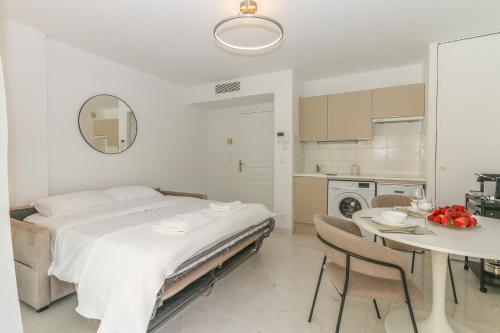 - une chambre blanche avec un lit et une table avec des chaises dans l'établissement Studio in Les Résidences du Palais, à Nice