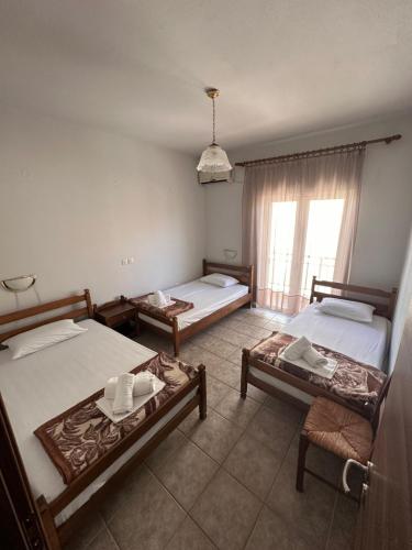 a room with two beds and a chair and a window at Teo rooms in Paralia Katerinis
