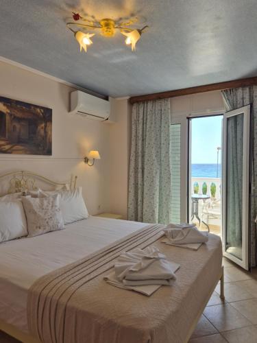 a bedroom with a bed with a ceiling fan and a window at Vrachos Beach Hotel in Vrachos