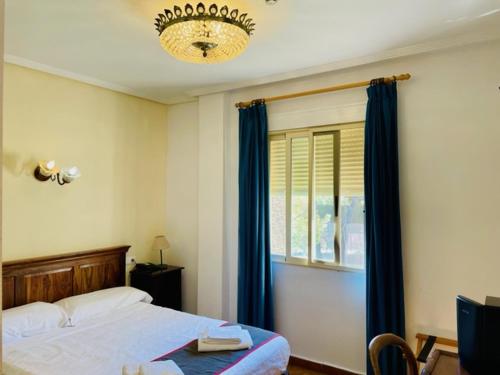 a bedroom with a bed and a window and a chandelier at Hotel Torre San Juan in San Juan de Alicante